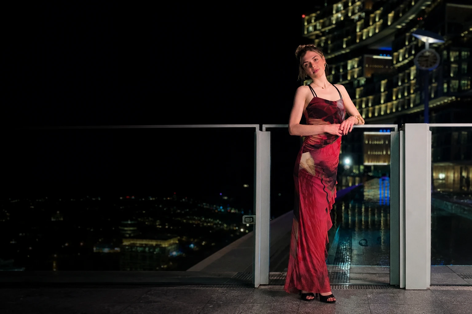 Olivia im roten Kleid auf einer Dachterrasse, Skyline im Rücken